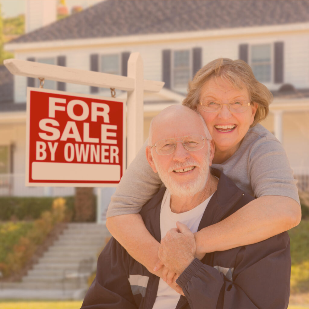 An older couple standing by a sign that reads "For Sale By Owner"