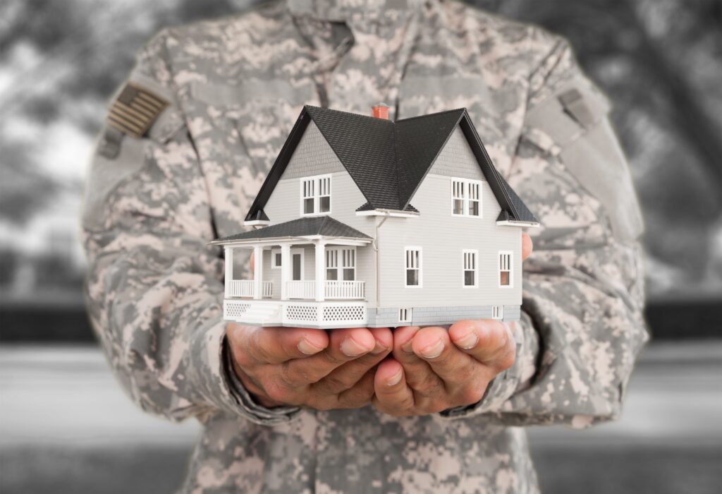 Military personnel holding a model of a house