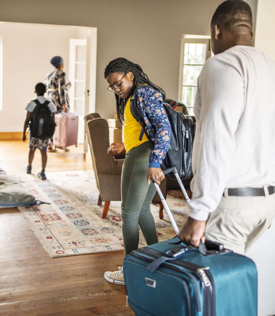 Girl and her family leaving a home with suitcases