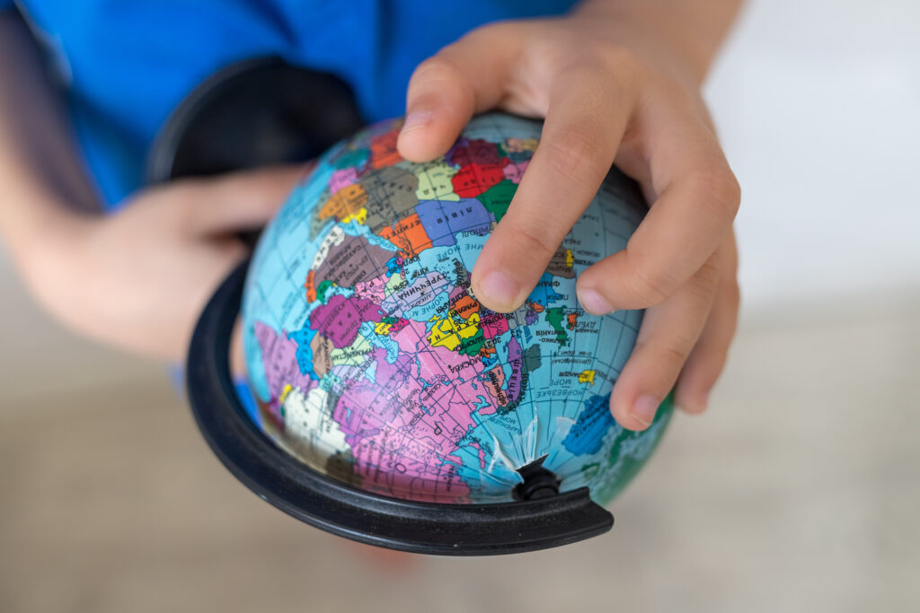 A hand pointing at a location on a globe