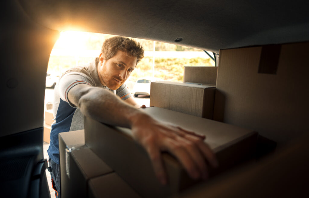 A military mover packing a box in the back of a moving van.