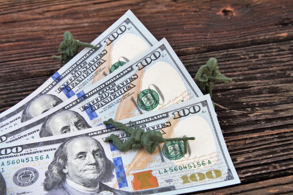 A stack of money with toy soldiers over it representing the money one gets from the Forever GI Bill.