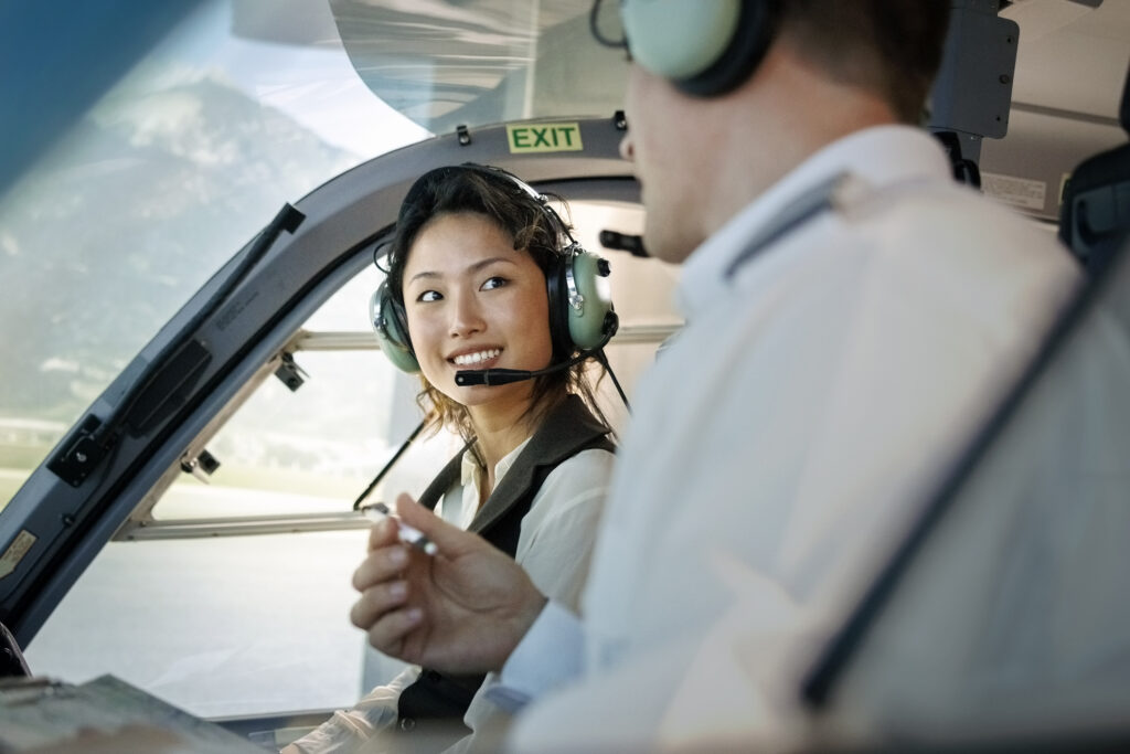 A flight instructor and a student pilot in a helicopter cockpit, talking during a flight school training session.